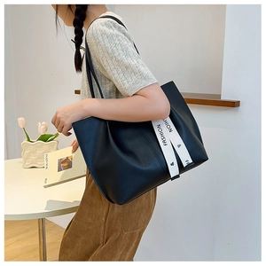 Detail of black PU leather tote bag featuring a decorative fashion letter strap on the side