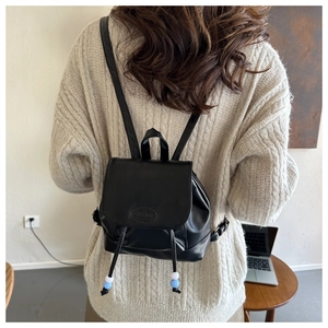 Vue arrière du modèle portant un mini sac à dos en cuir noir avec lettrage FASHION