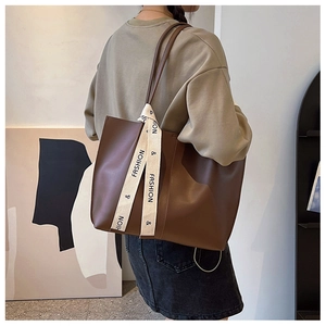 Close-up of brown large capacity tote bag with fashion printed strap detail