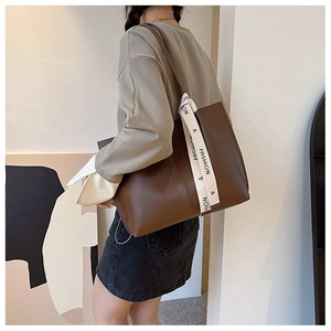 Detail of dark brown leather tote bag showing cream ribbon with fashion text print