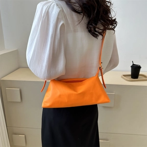Orange soft PU leather crossbody bag worn by model with adjustable shoulder strap