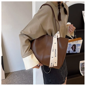 Detailed side view of brown PU leather tote bag with stylish white lettered strap