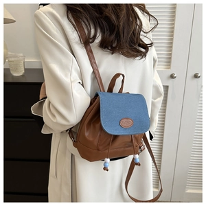 Détail d'un mini sac à dos en cuir marron avec rabat en denim bleu et cordon de serrage