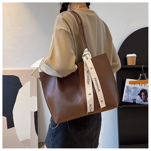 Detail view of large brown vintage PU leather tote bag with fashion lettered ribbon strap