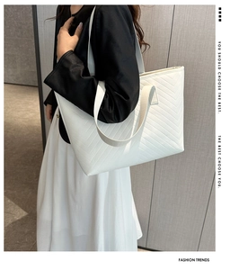 Detail of white quilted tote bag featuring V-shaped chevron texture and leather shoulder straps