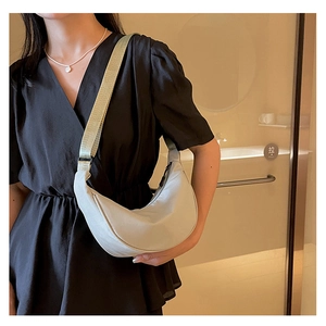 Dettaglio della borsa hobo in nylon grigio chiaro con ampia tracolla indossata da modella
