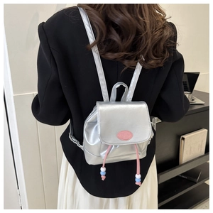 Détail mini sac à dos argenté avec cordon rose et écusson de mode pour femme chic