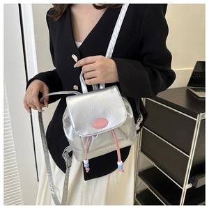 Détail d'un mini sac à dos argenté métallisé avec cordon rose et accents perlés