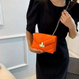 Borsa a tracolla arancione trapuntata con catena dorata e chiusura a T su modella