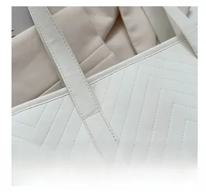 Detail view of reinforced stitching on a white quilted faux leather tote shoulder bag