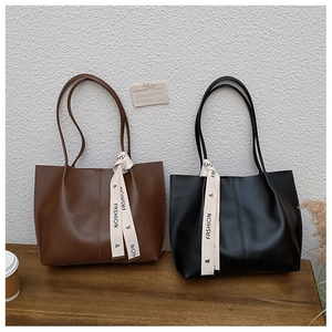 Detail of minimalist leather tote bags in brown and black with chic ribbon ornament