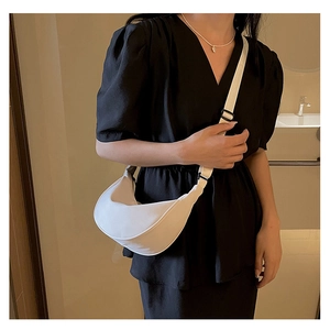 Dettaglio di una borsa a mezzaluna bianca minimalista con tracolla in tessuto regolabile