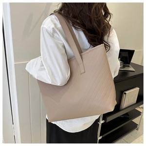 Detailed side view of large beige quilted tote bag on shoulder for daily commute