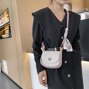 Elegant beige saddle crossbody bag with pink trim and a decorative silk bow detail