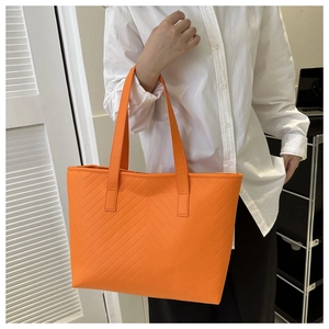 Detail of orange tote bag with V-shaped quilting and matte texture on shoulder