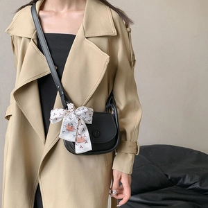 Minimalist black leather saddle bag with printed silk ribbon scarf and round embossed detail