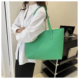 Close-up of a green V-quilted tote bag showing stitching and shoulder strap details