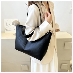 Detailed view of black tote bag featuring V-shaped quilted stitching on matte leather