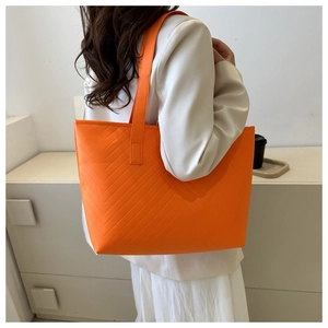 Close-up of bright orange tote bag with V-shaped stitching and slim shoulder straps