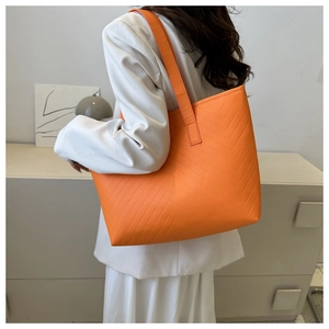 Detail of a bright orange quilted tote bag featuring a V-shaped textured pattern for women