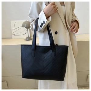 Modern black tote bag with chevron quilting shown on a model in a minimalist setting