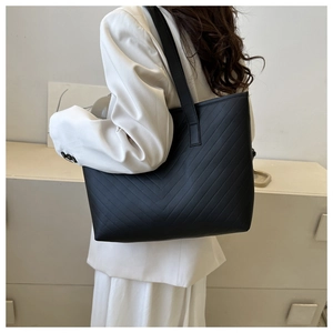Detail of black tote bag with V-shaped quilted stitching and wide shoulder strap