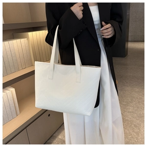 Close-up of a white tote bag featuring chevron stitching and long shoulder straps
