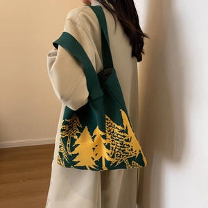 Knitted tote bag with green forest tree pattern and wide shoulder strap on model