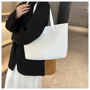 Lifestyle shot of a white quilted tote bag with V-shaped stitching on a model