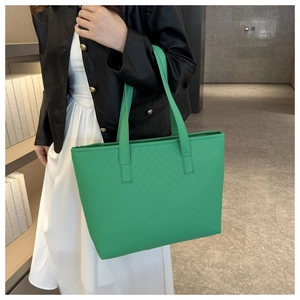 Detail of bright green tote bag featuring modern V-shaped quilted stitching and soft leather