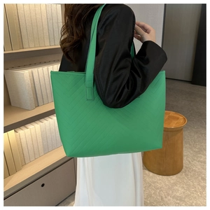Close-up of green tote bag with V-shaped quilted stitching in a minimalist interior