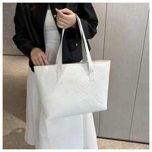 Close-up of white chevron quilted tote bag featuring elegant stitching and leather straps
