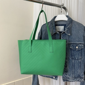 Close-up of bright green tote bag featuring detailed V-shaped quilting and long shoulder straps