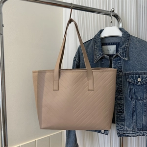Detail of light beige tote bag featuring V-shaped quilting and synthetic leather texture