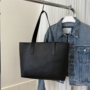 Macro view of minimalist black tote bag featuring classic V-shaped chevron quilted stitching