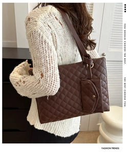 Detail view of large coffee brown quilted tote bag and matching mini pouch on model