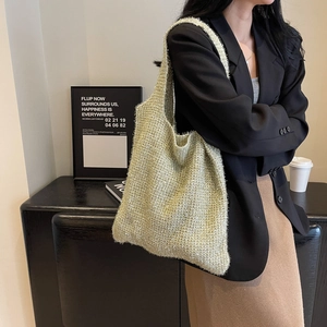 Luxe gold-green knitted hobo shoulder bag styled with a minimalist black blazer
