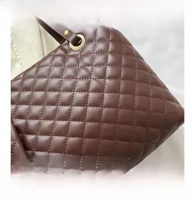 Detailed close-up of brown quilted leather tote bag with elegant gold metal eyelets
