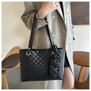 Detail of black quilted tote bag with matching mini pendant pouch and metallic strap rings
