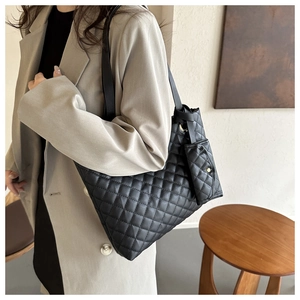 Close-up of black quilted tote bag with matching small pouch on a shoulder strap