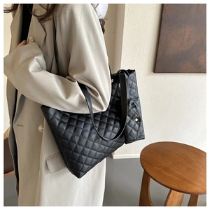Black quilted leather tote bag with small pouch worn by model for fashion styling