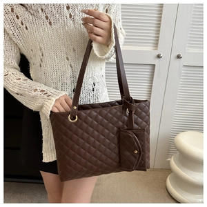 Detail view of brown quilted tote bag with matching pouch and golden hardware accents