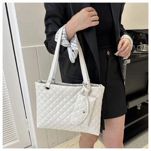 Close-up of white quilted tote bag with a small matching pouch and gold hardware