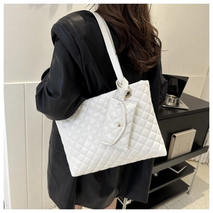 Detailed view of white quilted tote bag with matching pouch on model in office setting