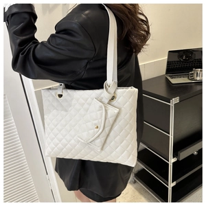 Detail of white quilted tote bag featuring a matching small pouch and gold hardware