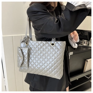 Close-up of silver quilted tote bag with matching pendant pouch on leather jacket model