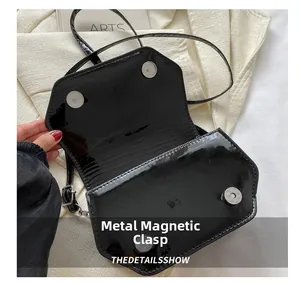 Macro view of the magnetic suction clasp and black patent leather interior of the square bag
