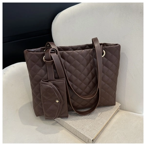 Detail of dark brown quilted tote bag with matching coin purse on a beige sofa