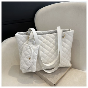 Detail of white quilted tote bag texture and matching small pouch on soft velvet chair