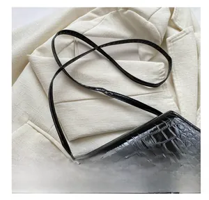 Detail of black crocodile texture bag with gold lettering on white suit blazer